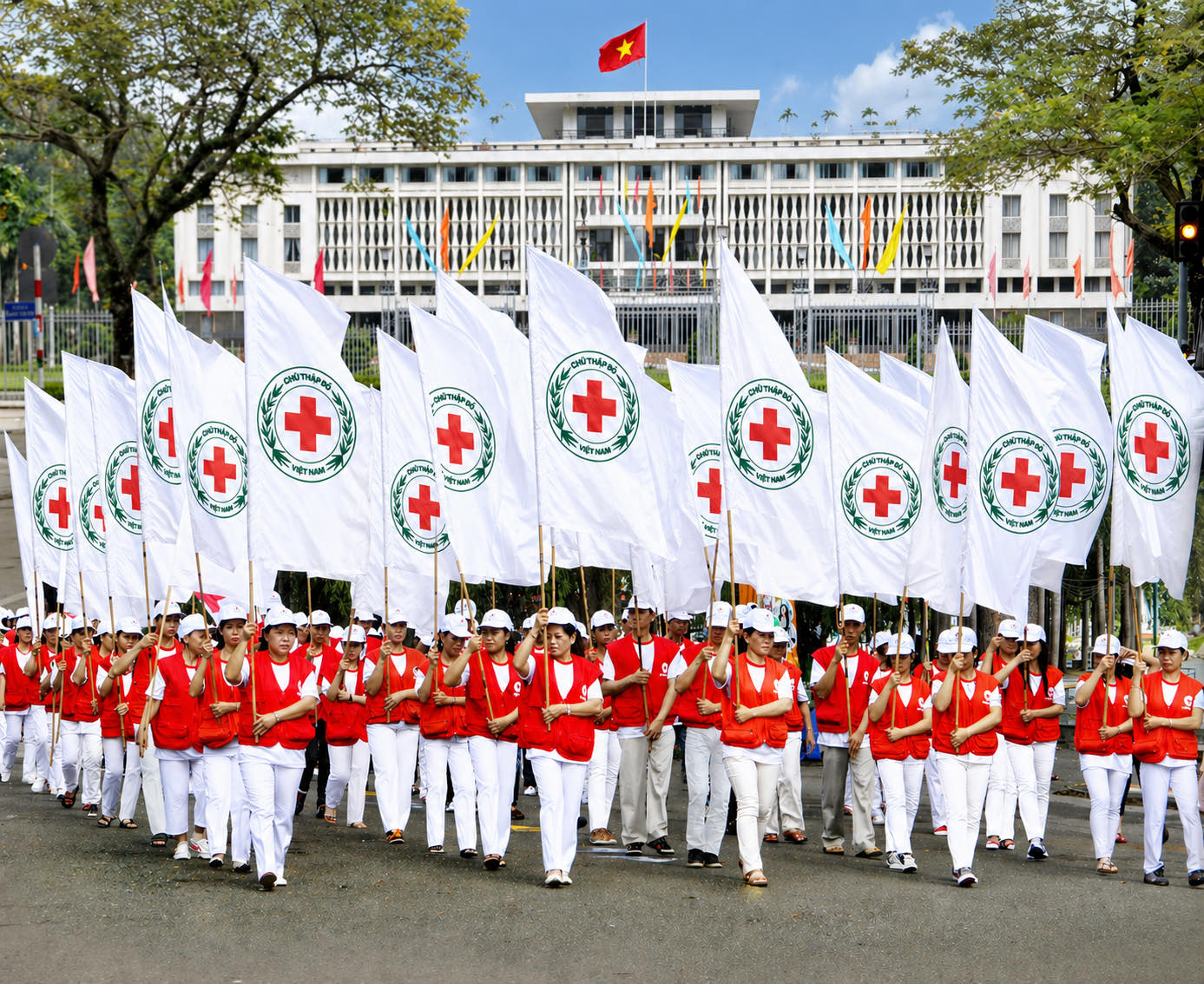 Đội hình tình nguyện viên Chữ thập đỏ cầm cờ Hội diễu hành trước Dinh Độc Lập
