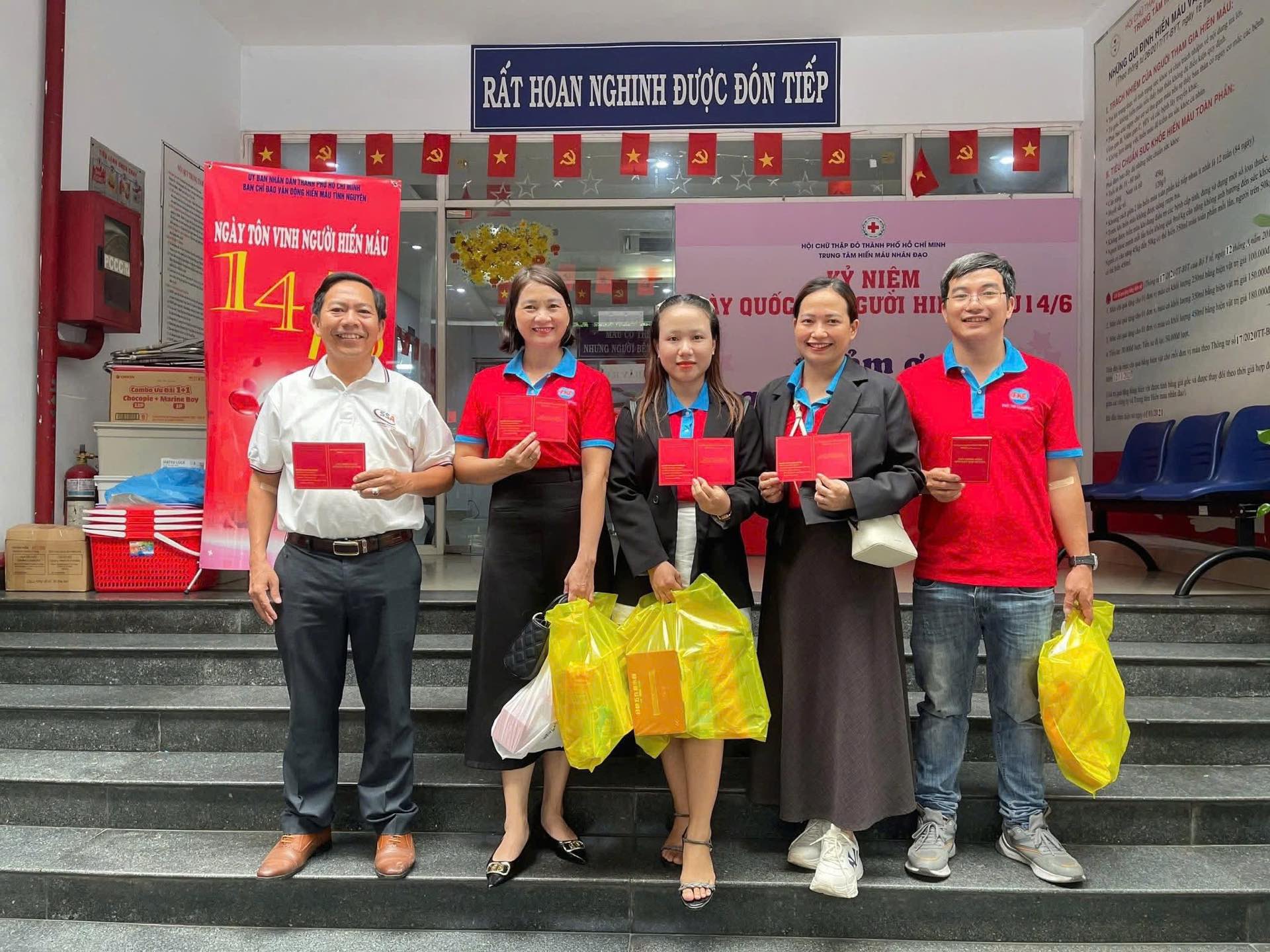 Năm người hiến máu cầm giấy chứng nhận đứng trước sảnh Trung tâm Hiến máu nhân đạo